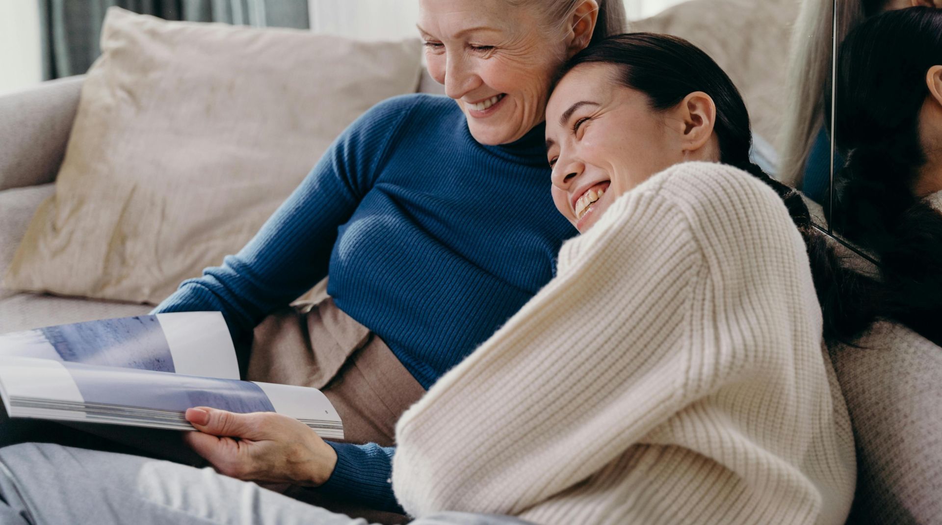 A joyful moment between a mother and daughter embracing each other on a sofa at home.